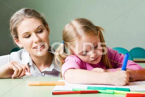 Portrait of diligent girl drawing something under tending of her teacher Stock Photos