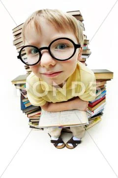Portrait of diligent pupil sitting on pile of books and looking at camera Stock Photos