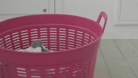 Portrait dirty clothes falling into the pink laundry basket Stock Footage 173720232
