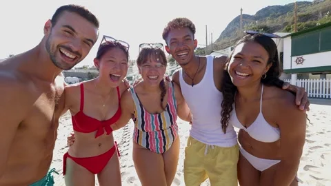 Portrait of diverse friends looking at camera hugging each other at beach Stock Footage 271666333