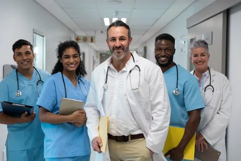 Portrait of diverse group of male and female doctors holding files, smiling in Stock Photos