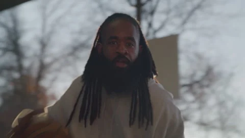 Portrait of Diverse Man with Dreadlocks Dribbling Basketball on Outdoor Court in Stock Footage 270398385