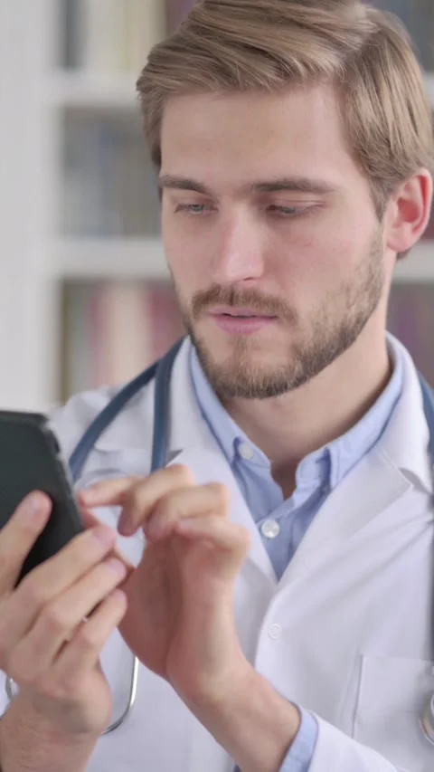 Portrait of Doctor using Smartphone, Vertical Video Vidéo 339577203