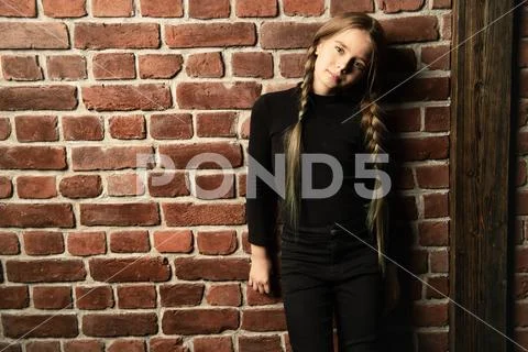 A portrait of a dreamy young girl posing in the studio over the brick wall. B Stock Photos