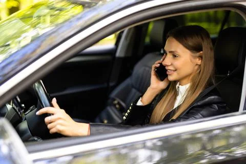Portrait of driver talking her mobile phone while driving car. Stock Photos