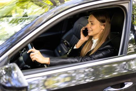 Portrait of driver talking her mobile phone while driving car. Stock Photos