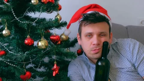 Portrait of drunk guy in red cap drinking wine of bottle at Christmas holidays. Stock Footage 136522471