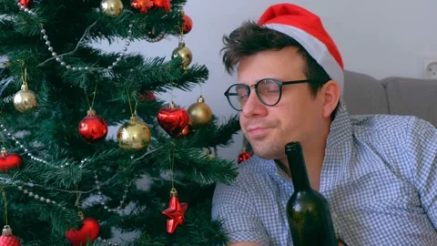 Portrait of drunk guy in red cap drinking wine of bottle at Christmas holidays. Video stock 137497146