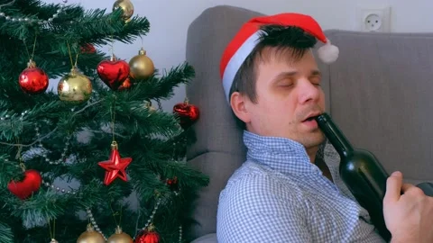Portrait of drunk man sleeping with bottle of wine on couch near Christmas tree. Stock Footage 136520651