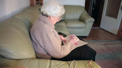 Portrait of an eighty year old senior woman recreating at home, doing crosswords Stock Footage 63598106