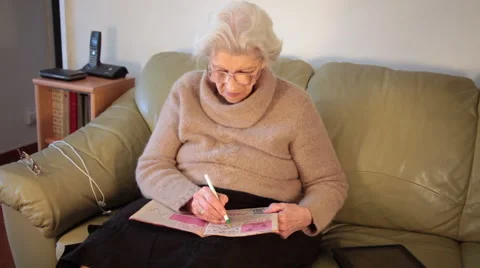 Portrait of an eighty year old woman doing crosswords at home, recreating Stock Footage 63598224