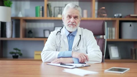 Portrait elder gray-haired experienced senior doctor sitting at desk in workplac Stock Footage 172492474