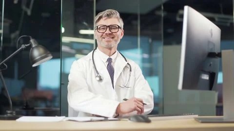 Portrait elder gray-haired experienced senior doctor sitting at desk in workplac Stock Footage 196990909