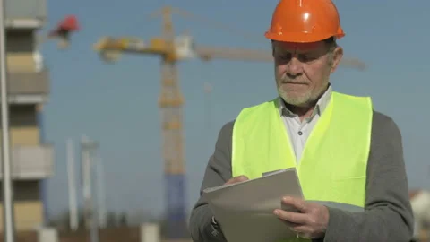 Portrait of an elderly builder. Against the background of an object under Stock Footage 127485297