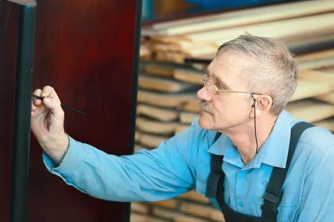 Portrait of an elderly carpenter at work in a carpentry shop. Stock Photos