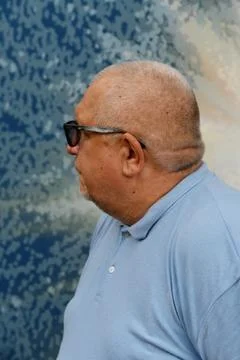 Portrait of an elderly gray-haired man in a blue polo shirt and sunglasses .. Stock Photos