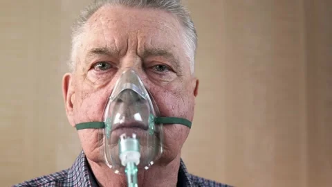 Portrait of an elderly man with COPD in an oxygen mask is breathing deeply 스톡 동영상 130744653