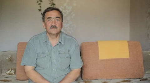 Portrait of elderly man with a mustache looking at camera at home on sofa Stock Footage 65374618