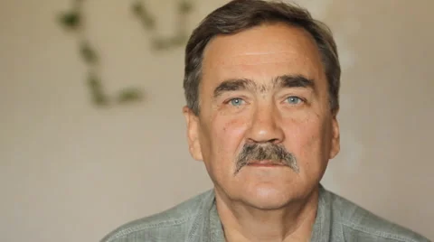 Portrait of elderly man with a mustache looking at camera at home on sofa Stock Footage 65374884