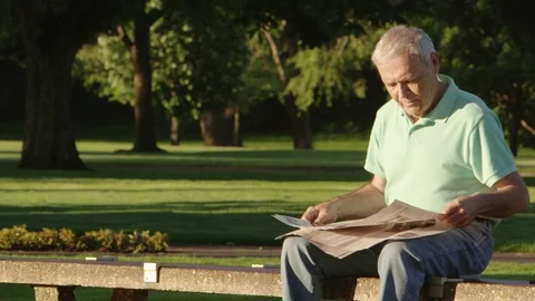Portrait of elderly man reading newspaper in the park Stock-Footage 80133641