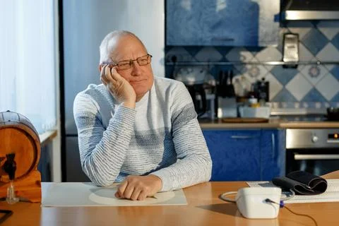 Portrait of an elderly man sitting at a table after measuring blood pressure  Stock Photos