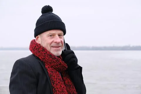 Portrait of elderly man talking on mobile phone on frozen lake. Stock Photos