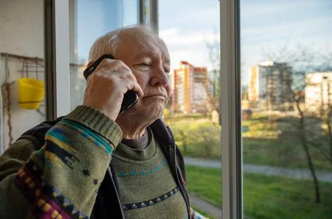Portrait of an elderly man using a smartphone. Elderly man near the window .. Stock Photos