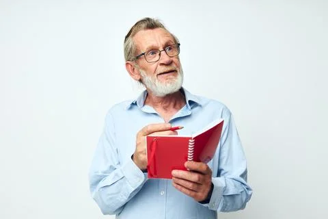 Portrait elderly man writes down emotions in a notebook light background Stock Photos