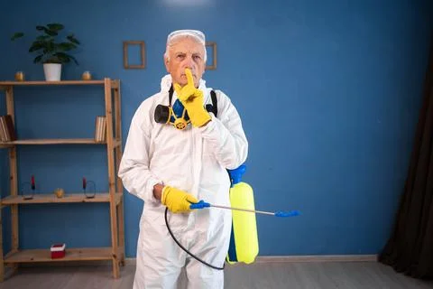 Portrait of Elderly pest control worker killing insects inside infested house Photos