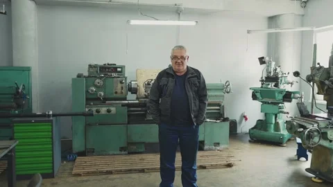 Portrait of an elderly professional turner in a work suit next to lathes in Video stock 281582607
