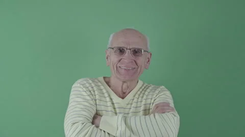 Portrait of elderly smiling man wearing his glasses against green cloth with Stock Footage 266722487