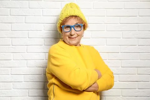 Portrait of elderly woman in hipster outfit near brick wall Stock Photos