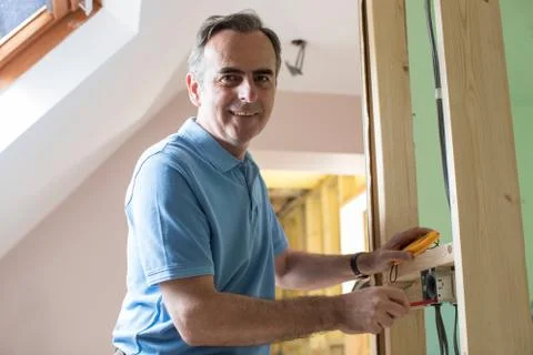 Portrait Of Electrician Installing Socket In New House Stock Photos