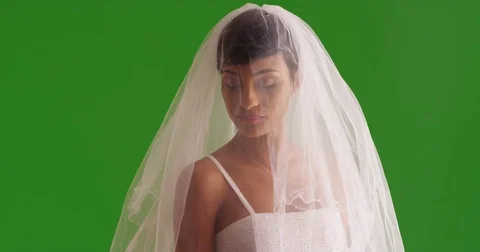 Portrait of elegant bride posing with veil covering face on green screen Stock Footage