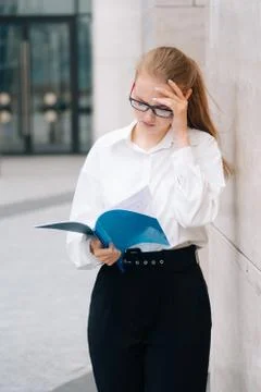 Portrait of an elegant brooding business lady girl in glasses holds a folder  Stock Photos
