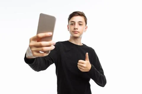 Portrait of an emotional teenager who takes a selfie on a smartphone, in a bl Stock Photos