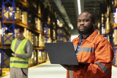Portrait of employee checking inventory data on laptop in logistics warehouse Foto stock