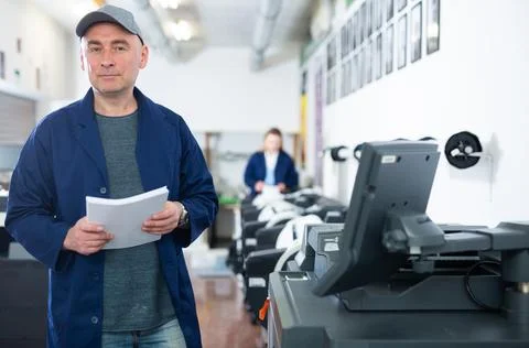 Portrait of an employee of printing house with stack of paper in his hands 스톡 사진