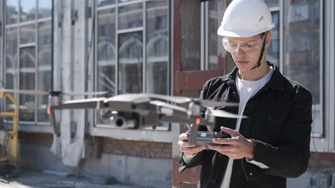 Portrait of engineer construction worker in helmet controlling flying drone Stock Footage 106236031