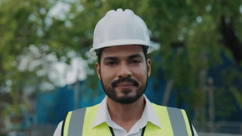 Portrait of engineer in hardhat and vest looking in camera at construction site Stock Footage 305685566