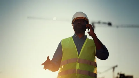 Portrait of engineer or foreman talking by mobile phone on building area Stock Footage 318709853