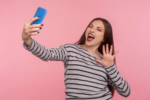 Portrait of enthusiastic woman in striped sweatshirt taking selfie on mobile  Stock Photos