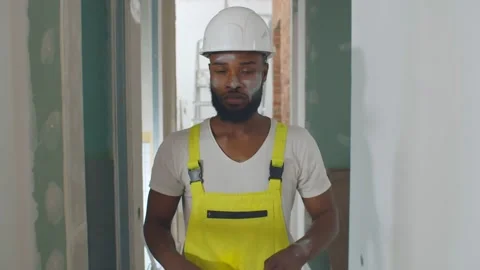 Portrait of exhausted afro-american builder removing safety equipment finishing Stock Footage 142209402