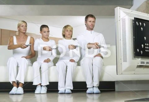 Portrait of Family Sitting on Sofa, Using Remote Controls Watching Television Stock Photos