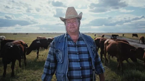 Portrait of a farmer in a field surrounded by cows. The rancher in a cowboy hat. Stock Footage 152941620