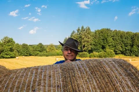 Portrait of a farmer in a hat behind a haystack in the field.. Stock Photos
