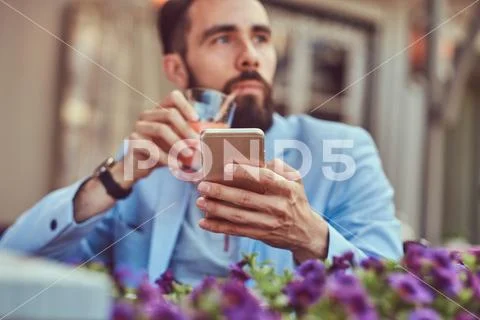 Portrait of a fashionable bearded businessman with a stylish haircut, drinks a Stock Photos
