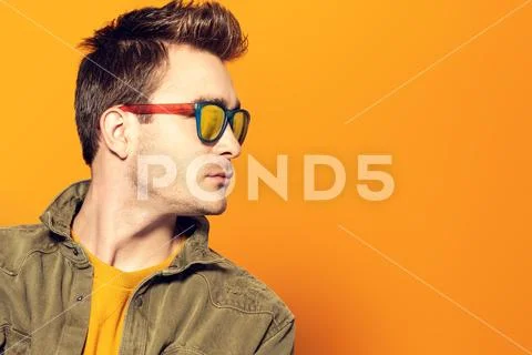 A portrait of a fashionable young man posing in the studio over the yellow ba Stock Photos