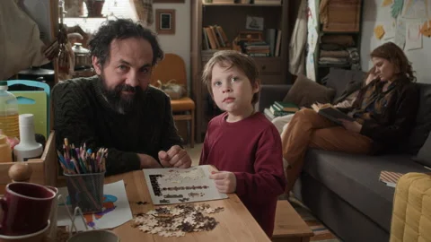 Portrait of Father and Son Putting Together Puzzle at Table in Poor apartment Stock Footage 337167883