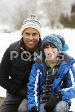 Portrait Of Father And Son Wearing Winter Clothes In Snowy Landscape Stock Photos